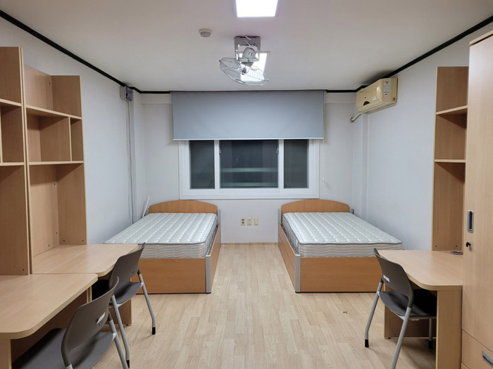 2인실을 정면에서 바라 본 모습으로 좌우에 책상과 사물함이 있고 그 옆에는 침대가 배치되어 있으며 머리맡에는 창문과 블라인드가 설치되어 있다.  